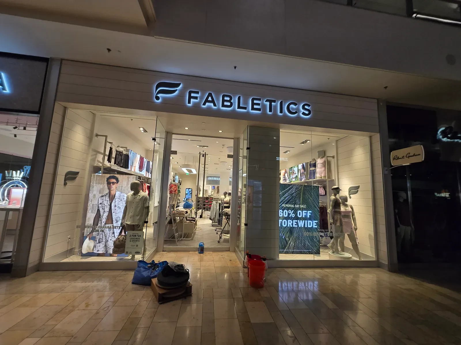 Cleaning equipment set up on the tile floor outside a retail store in a shopping mall