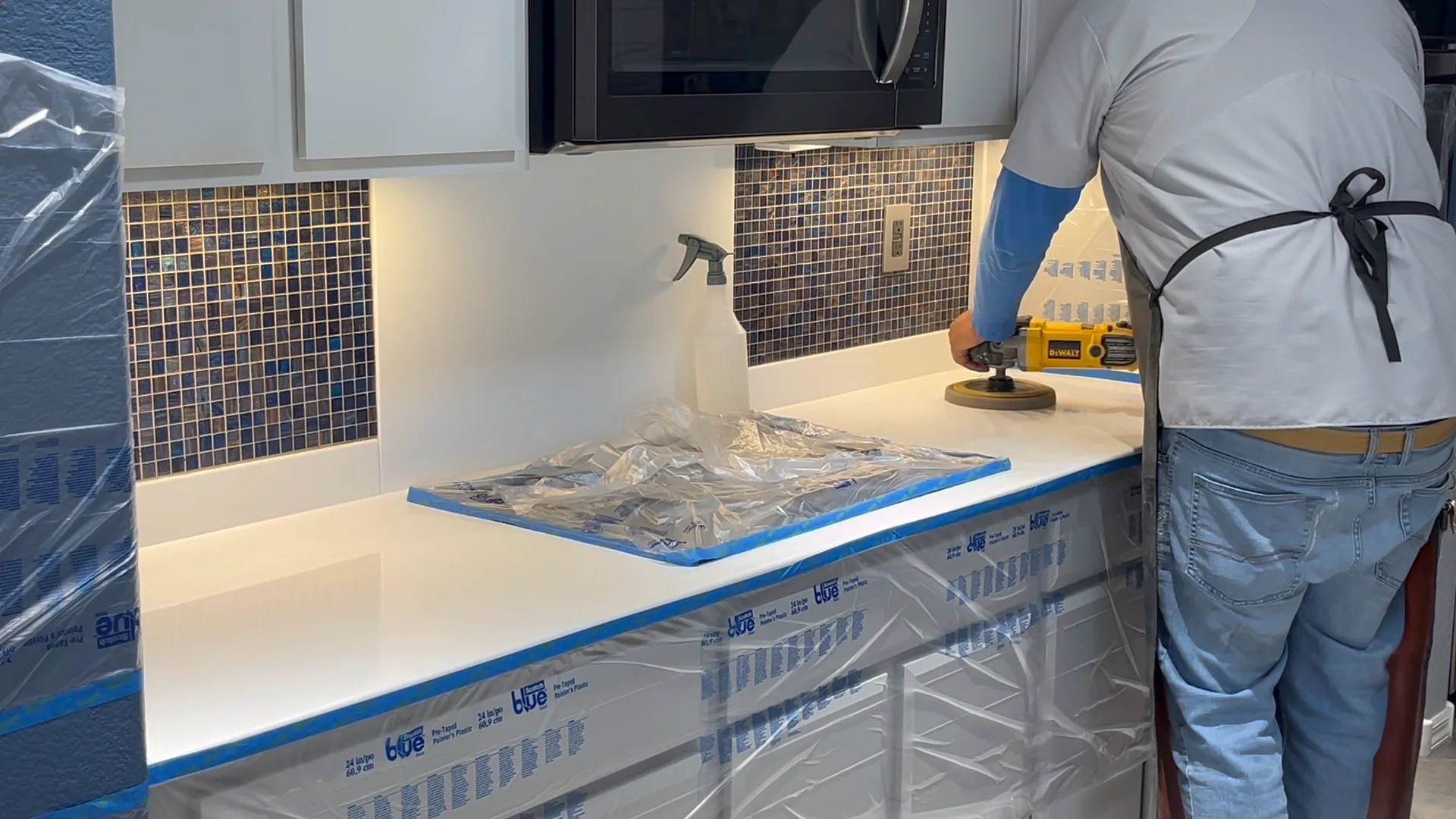Polishing a white Corian kitchen countertop with a DeWalt orbital in a residential home