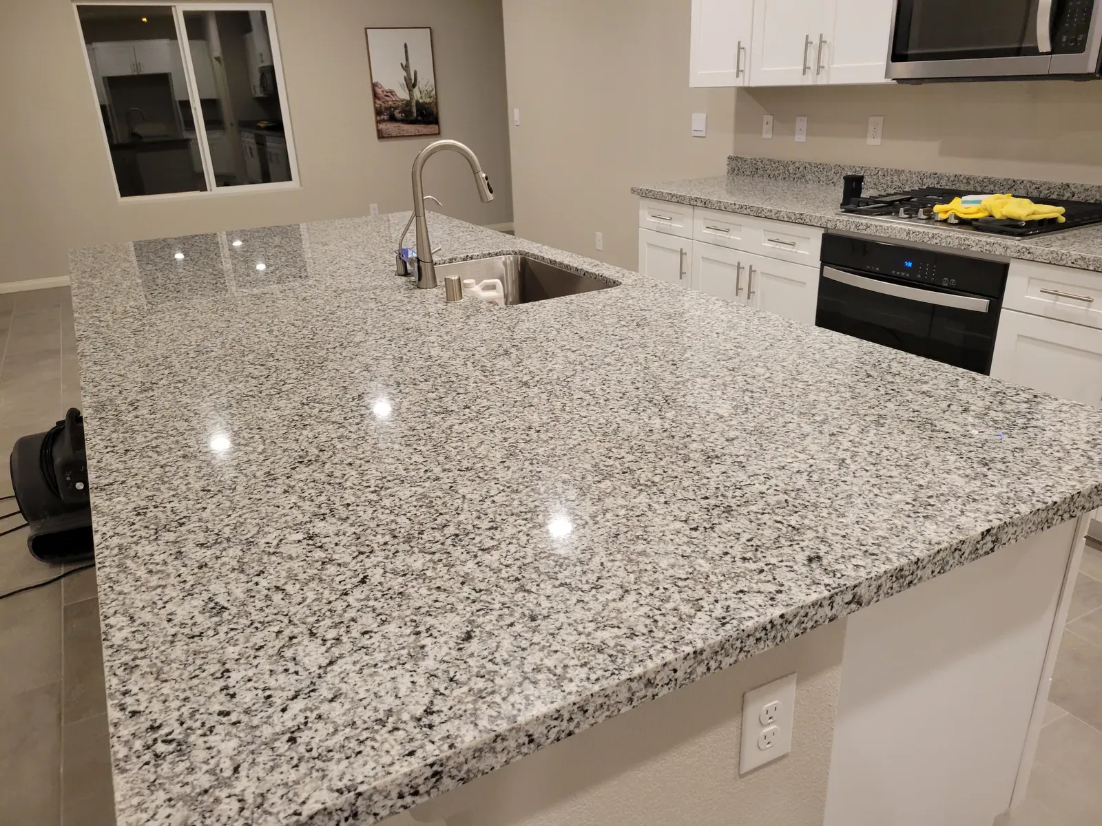 Sealed speckled granite kitchen island and peninsula with a glossy finish in a residential home