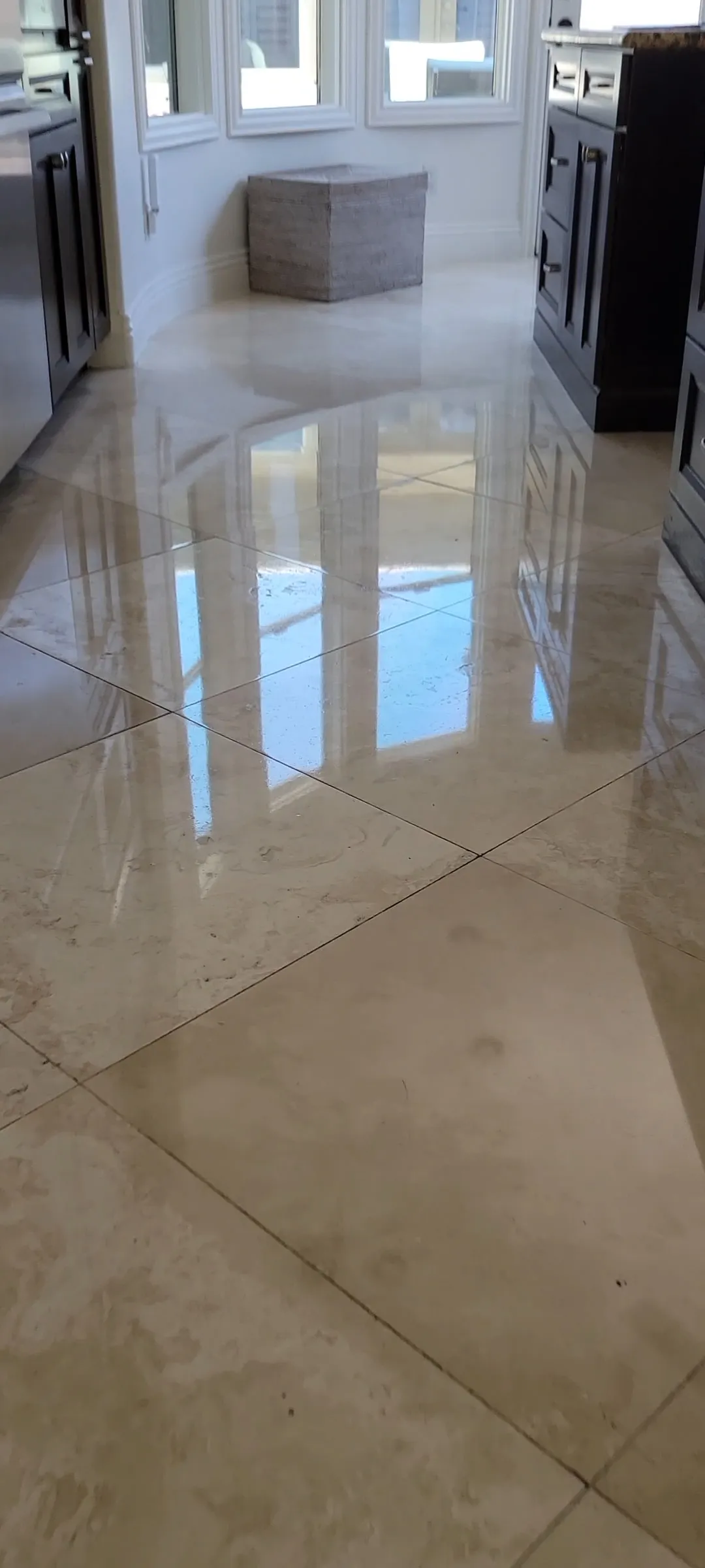Mirror-polished marble tile floor in a residential kitchen reflecting natural light