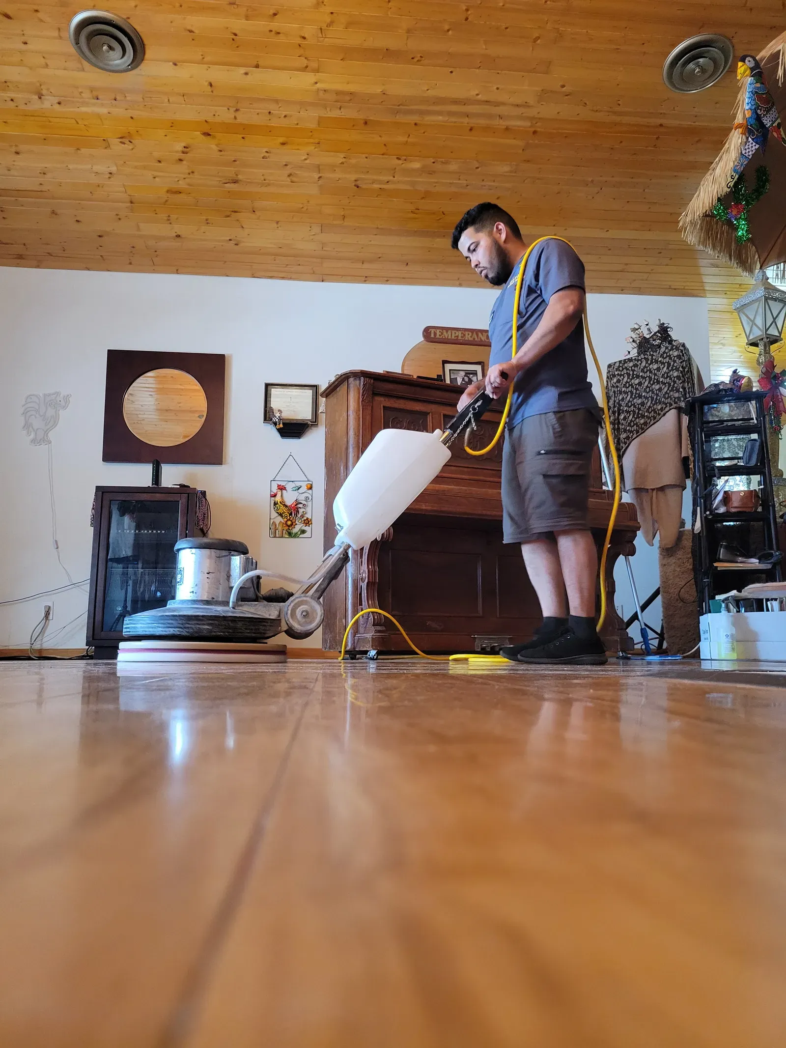 Technician polishing a glossy stone floor with a rotary machine in a residential home