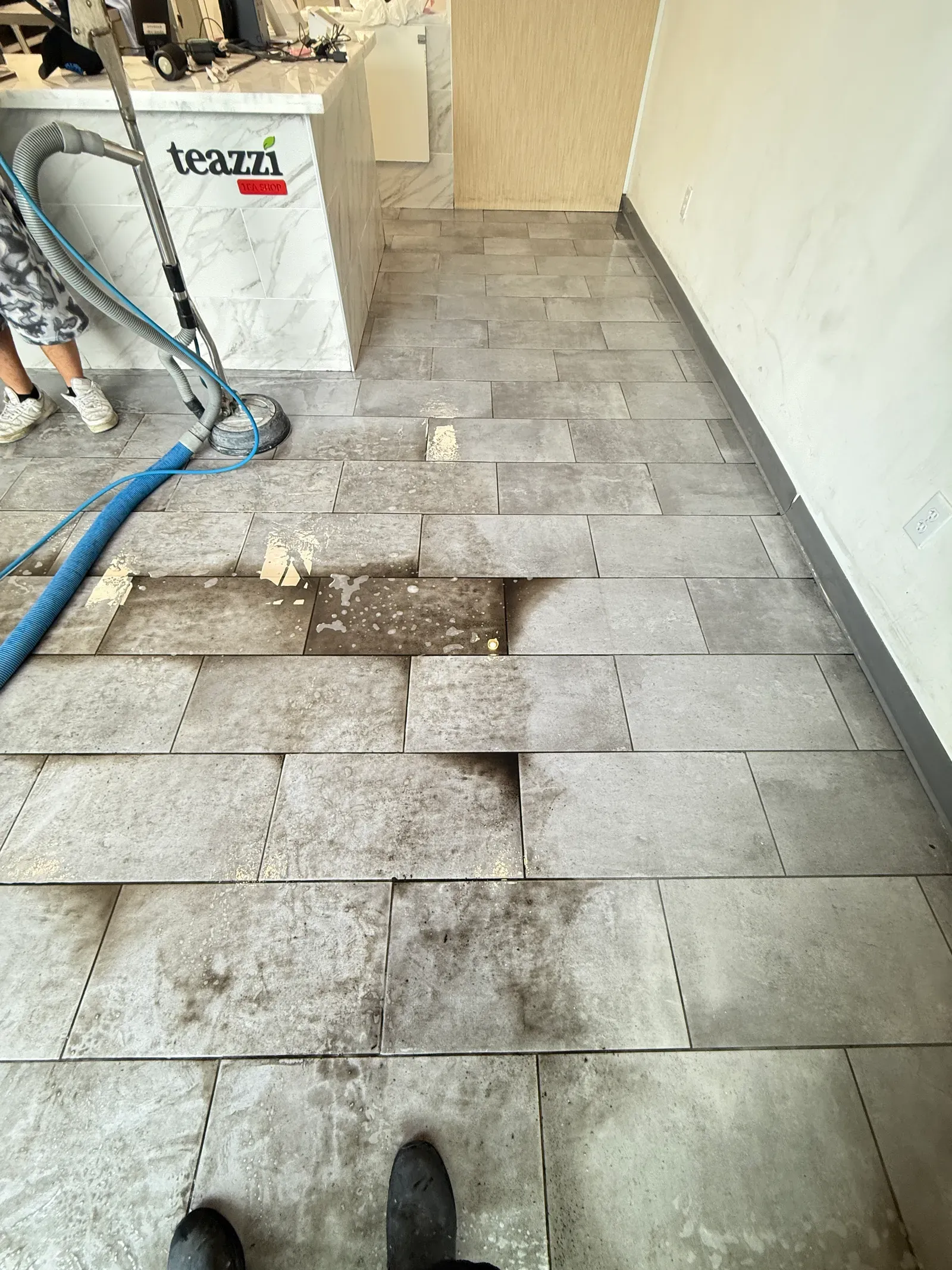 Deep cleaning a gray tile floor with a spinner tool at a Las Vegas tea shop
