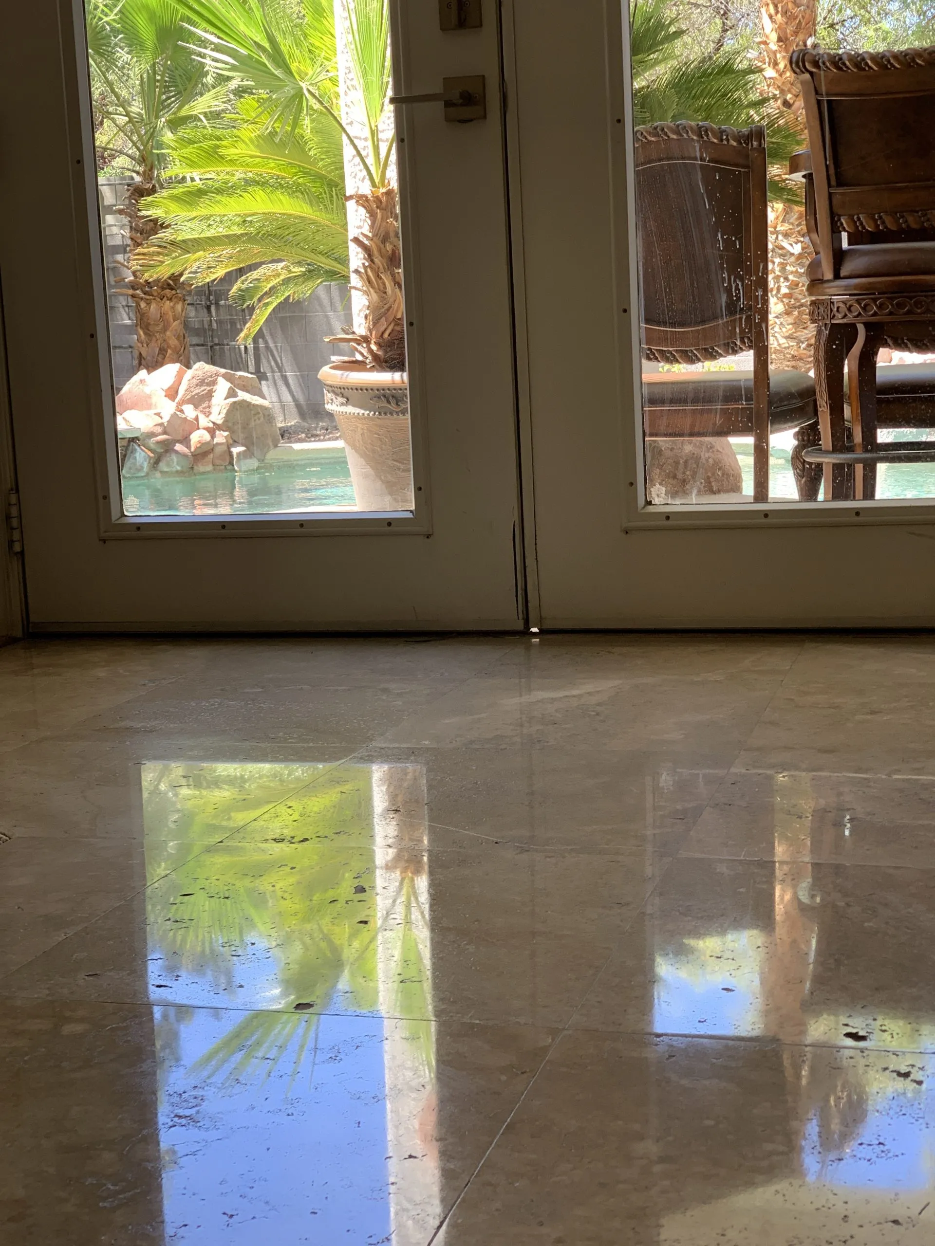 Polished travertine flooring at a back door with pool view in a residential home